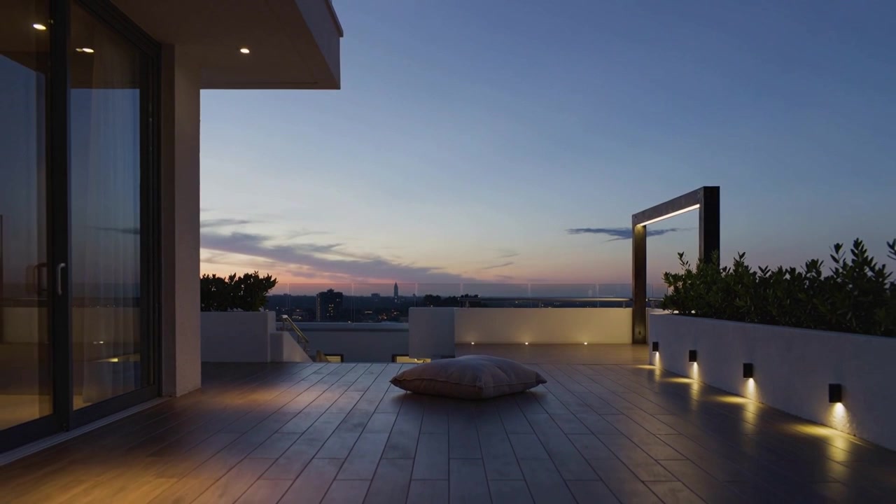 Sunset fading, rooftop terrace lights brightening while large floor cushion sitting on wooden deck