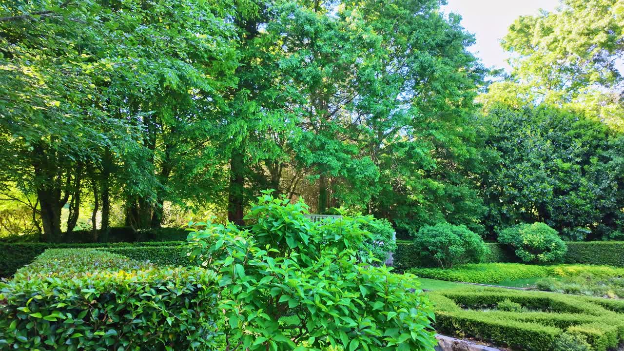 Peaceful shady garden corner with trimmed hedges and tall trees at Upper Brittany Botanical Park, Le Chatellier, France.