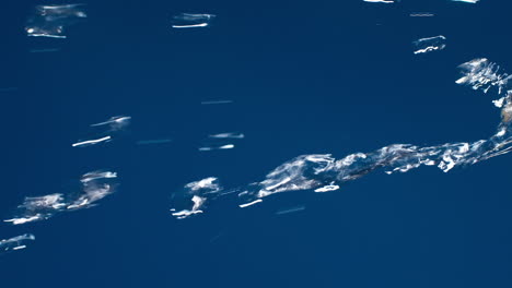 vertical de agua pura real que fluye hacia abajo con salpicaduras sobre fondo azul disparando en cámara lenta