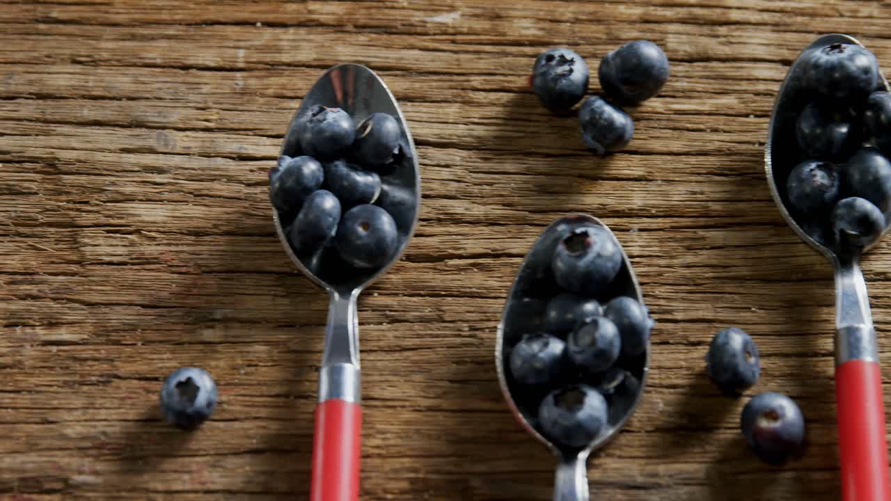 Spoons of blueberries arranged on wooden table 4k