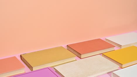 stack of hardcover books in pastel colors changing places on orange theme. stop motion