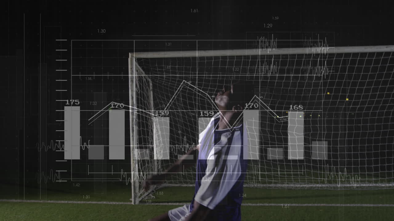 male soccer player raising arms in front of goal at night, showing sports analytics overlays
