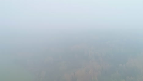 Aerial-drone-backward-moving-shot-of-rainforest-landscape-with-lakes-covered-with-dense-clouds-at-daytime