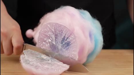 cutting into fluffy cotton candy to reveal a surprise clear object inside