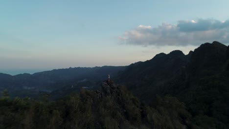 kandungaw peak with blond travel girl standing on rocky edge during sunset