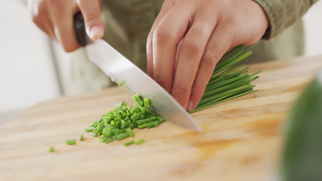 Video of hands of biracial woman cutting chives