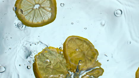 lemon dropped transparent water closeup. yellow vitamin fruit floating in liquid