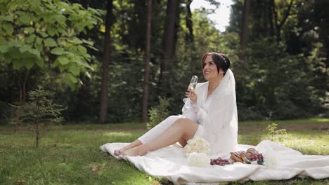 wedding bride in boudoir dress sitting in morning garden drinking champagne woman in night gown veil