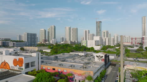 Aerial-ascending-footage-of-various-buildings-in-city.-High-rise-apartment-houses-on-waterfront-in-background.-Miami,-USA