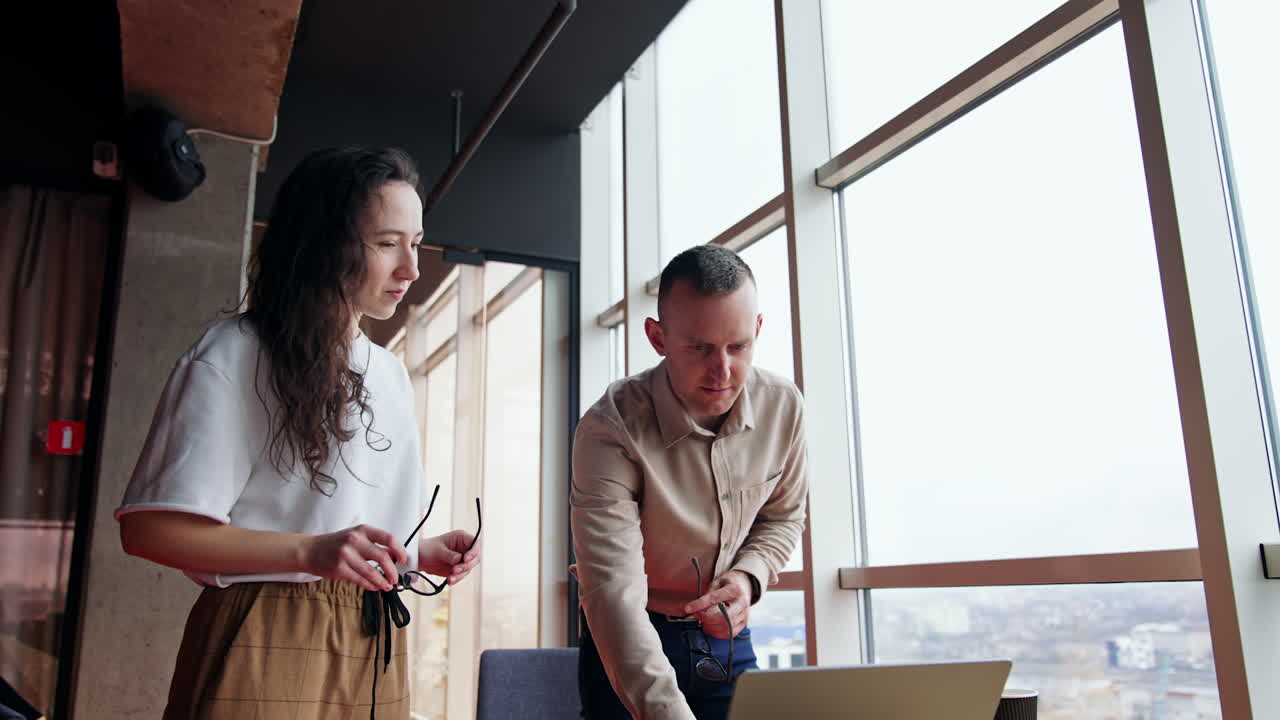 Man helping his female colleague with her laptop. Computer help in the office. Low angle view.
