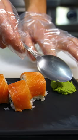 professional chef hand decorate sushi roll on a serving plate to custom. chef preparing delicious sushi menu fish with rice in japanese restaurant. vertical video