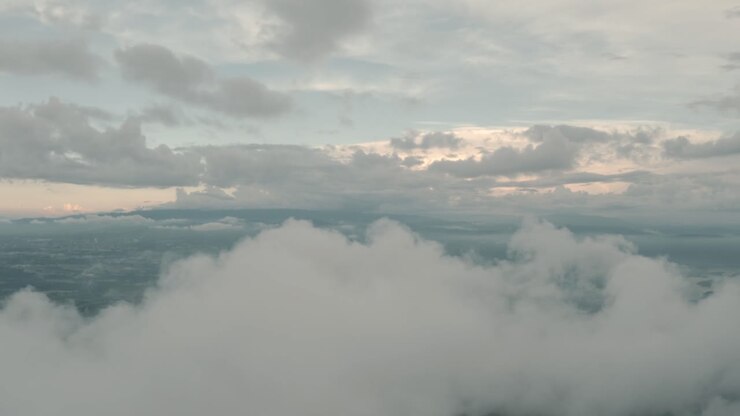Drone aerial rising shot over clouds moving in a beautiful cloudy and misty day
