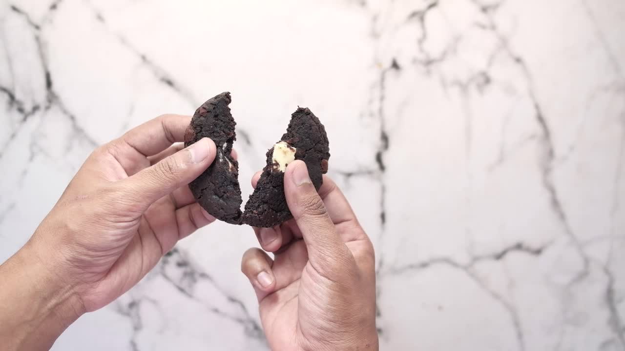 manos sosteniendo una deliciosa galleta de chispas de chocolate con relleno de chocolate blanco