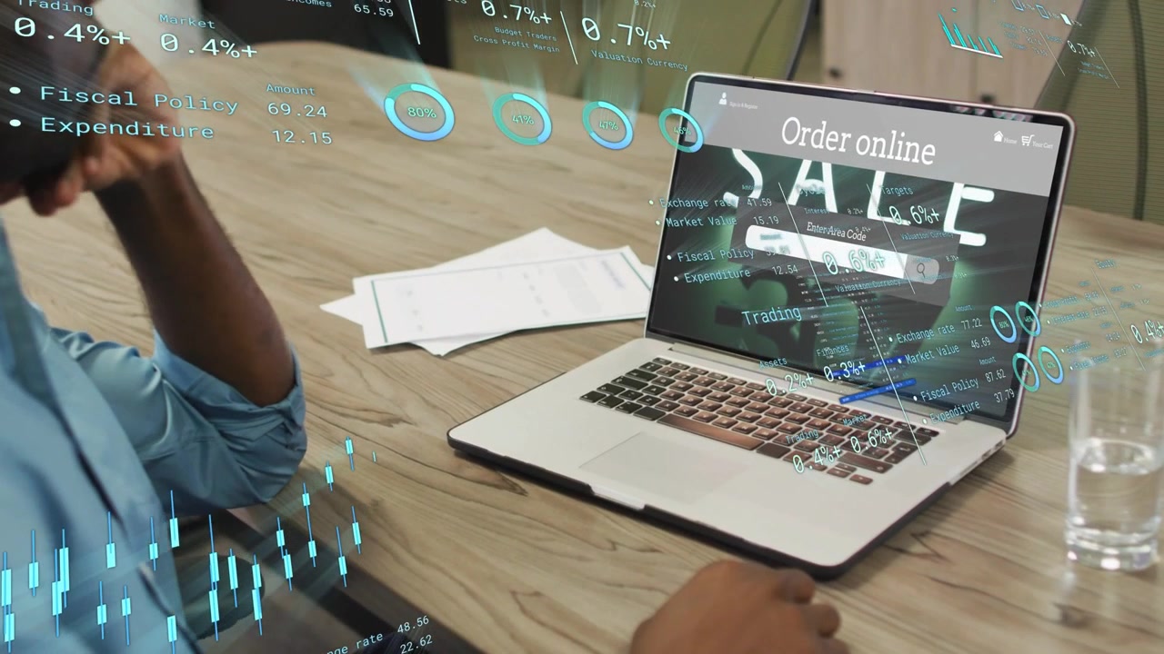 Lavoratore che sposta la mano destra sul trackpad e analizza le vendite e-commerce con sovrapposizioni HUD di SALDI sul laptop.