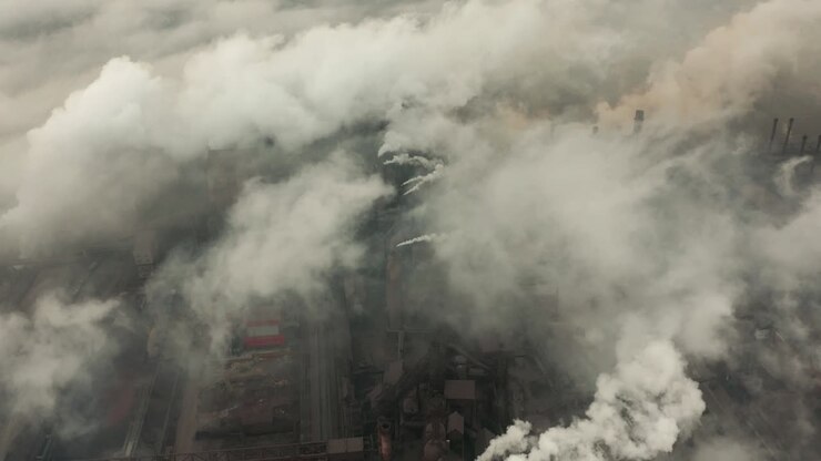 Aerial view of an industrial pipe pollutes the air next to people living in the city. Create a Greenhouse effect