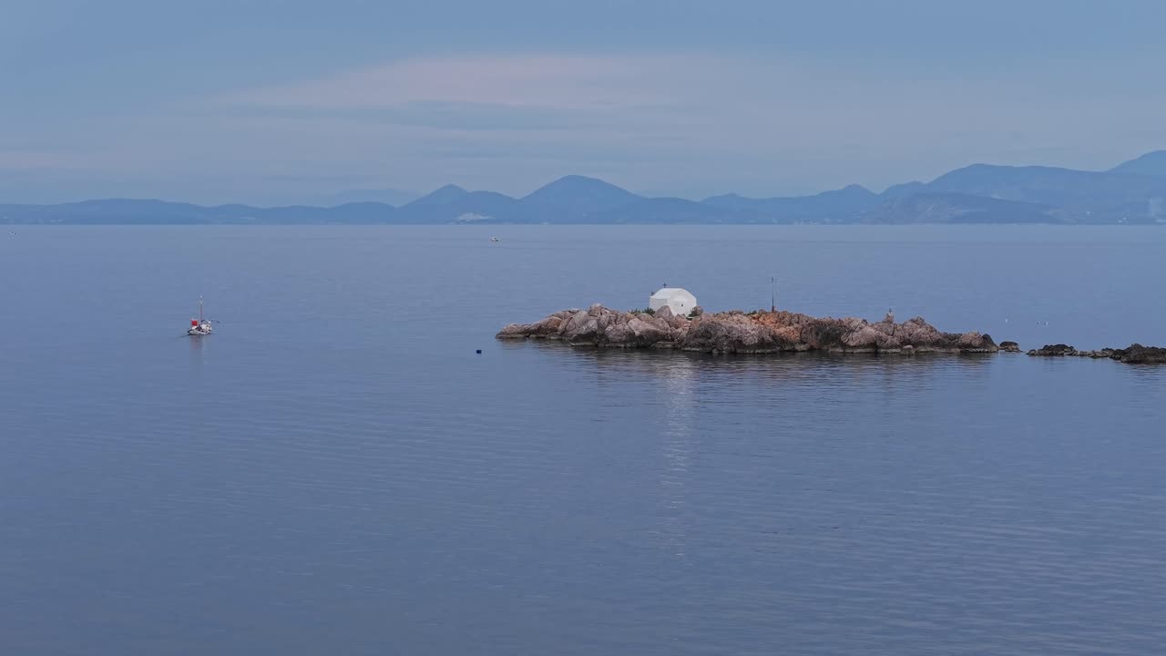 Ripresa aerea invernale dell'isola di Hydra, che mostra l'iconico taxi boat utilizzato per il trasporto che scivola agevolmente sul mare calmo vicino al porto