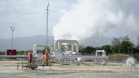 geothermal station with steam and pipes in the rainforest. billowing steam from smoke stack filling sky, buharkent, turkey