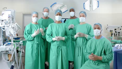 portrait of diverse surgeons wearing surgical gowns in operating theatre, slow motion