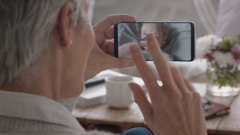 mature woman having video chat using smartphone grandmother waving at baby enjoying chatting to grandchild on mobile phone screen 4k footage