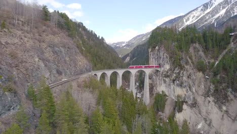 Aerial-view-of-the-famous-Bernina-Train-coming-out-the-mountain-tunnel