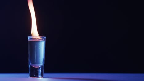 video of lit alcohol in glass with yellow fire flames and copy space on black background