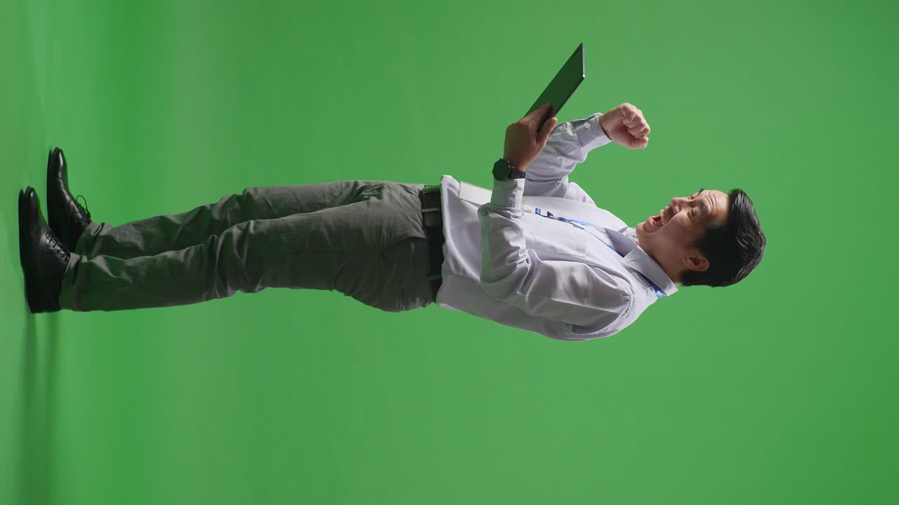 비즈니스맨이 녹색 화면에 태블릿으로 성공을 축하하고 있습니다.