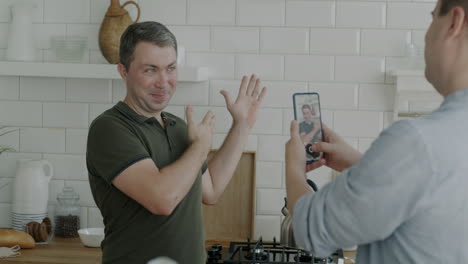 man video chatting while making a thumb up gesture in a kitchen