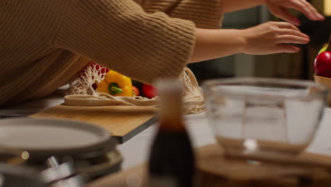 close up of woman unpacking bag of fresh healthy vegetables onto counter in kitchen