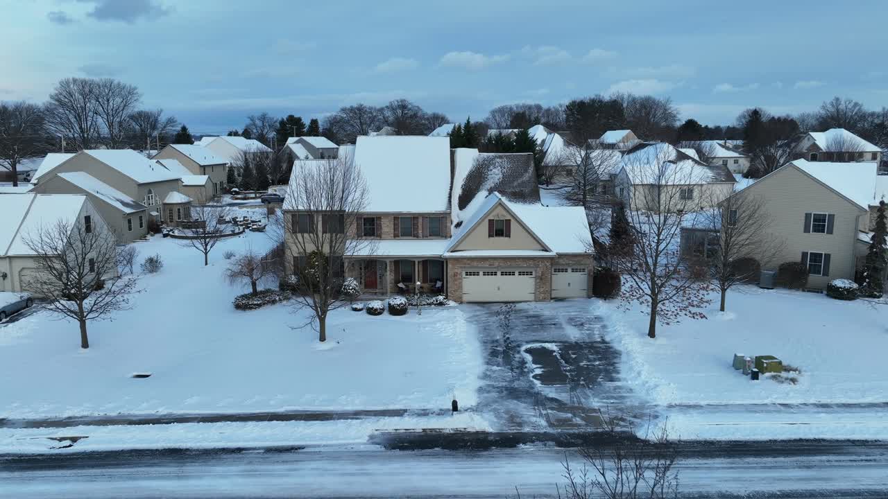 Aerial view of a snowy suburban neighborhood with modern homes, streets lightly dusted with snow, captured in the USA.