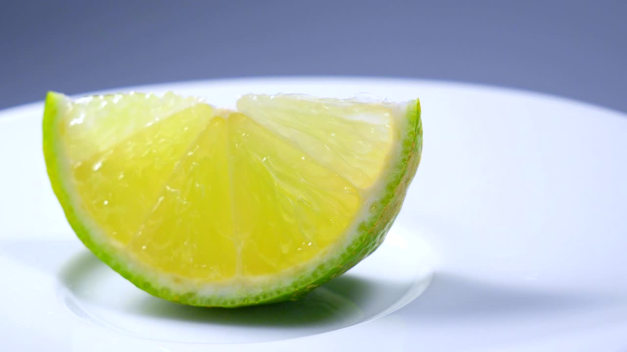 una rebanada de limón verde está girando lentamente en el estudio con los detalles.