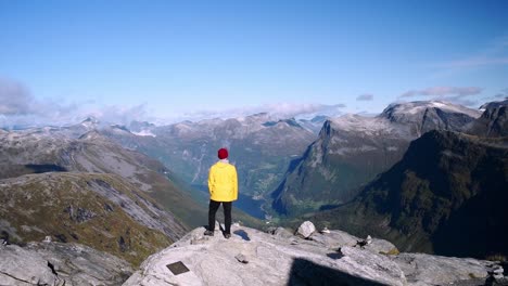 man in a yellow coat standing on the edge of a cliff