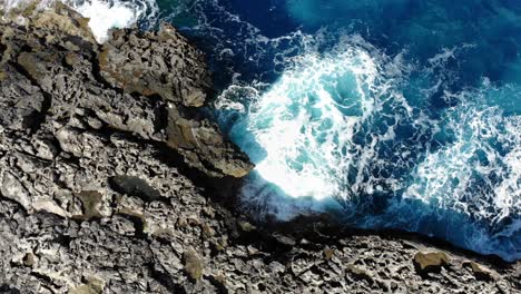 waves crashing in rocky coastline mellieha malta, aerial top sideways view