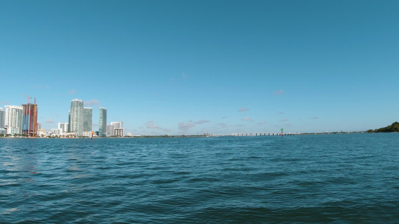 미아미 시가 왼쪽에 있는 비스케인 만의 물을 따라 빠르게 달리는 작은 보트에서 볼 수 있습니다.