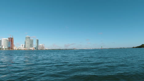 view from a small boat speeding along the water of biscayne bay with the city of miami off to the left