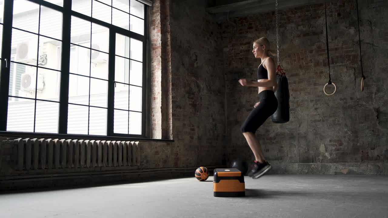 계단 플랫폼에서 점프하는 여성 느린 동작. 여성 다리 운동화 체육관에서 활발한 운동