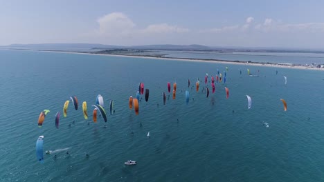 gran grupo de kitesurfistas compitiendo, vista por un dron. costa de un día soleado