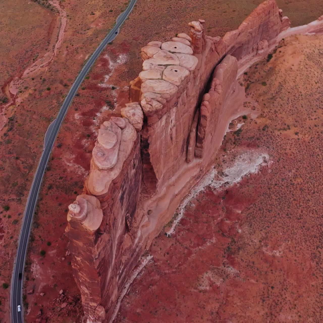 Stunning beautiful flat rock located in the middle of desert. Drone flight over the rounded peak mount and road passing below it. Top view