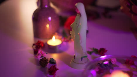 close up of prayer candle and tarot cards in ceremonial setting with soft pink ambient lighting