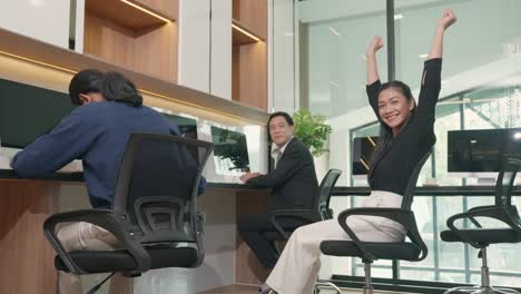 asian business teamwork sitting on chair looking screen of computer with raised hands and having fun celebrate victory