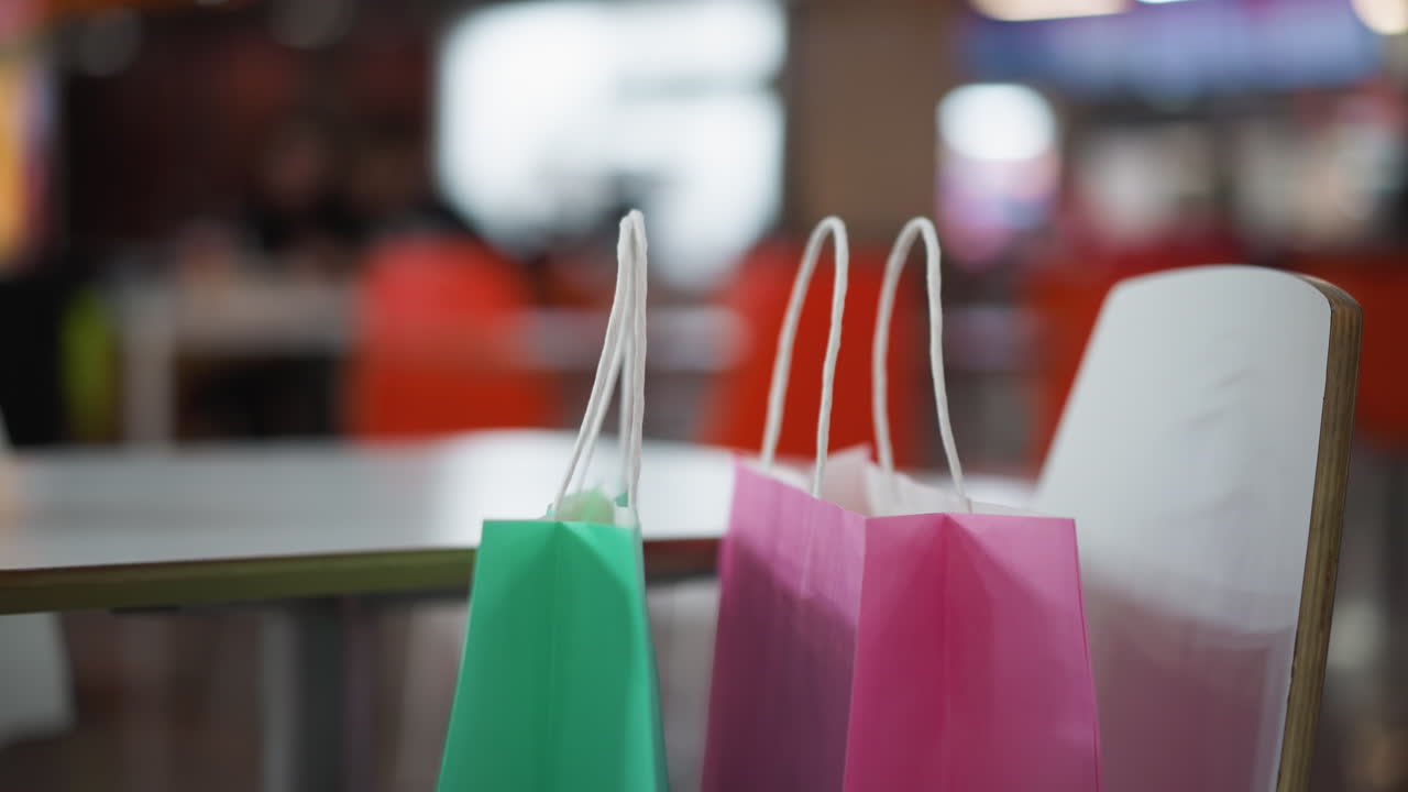 primer plano de bolsas de compras coloridas en la mesa con fondo borroso del centro comercial, iluminación suave que ilumina la escena, ideal para conceptos de compras, ocio, consumismo y estilo de vida del centro comercial