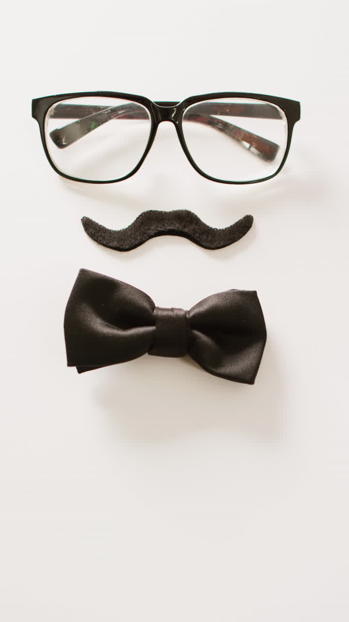 video vertical de bigote falso negro, gafas y pajarita sobre fondo blanco con espacio para copiar