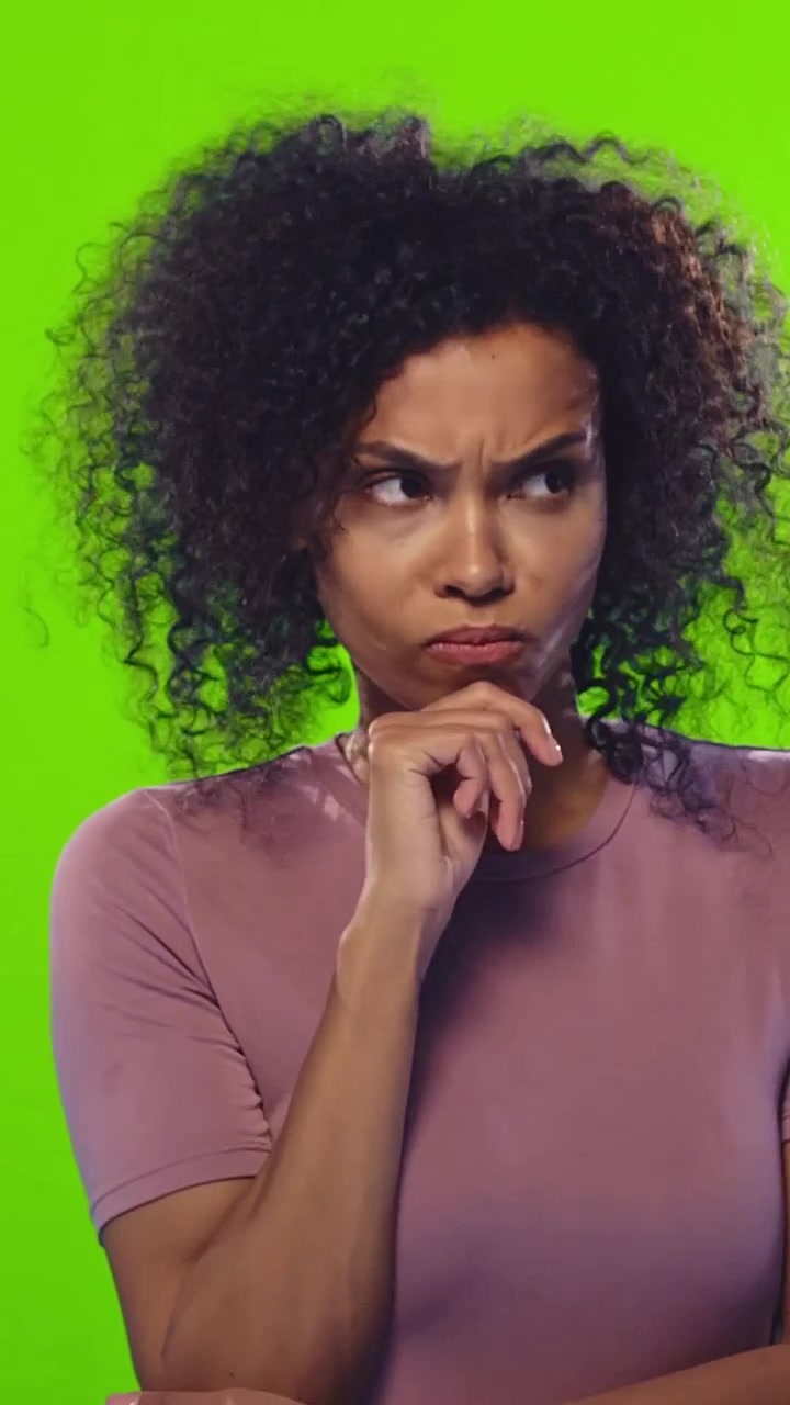Pensive serious african american young woman touches her chin looking away