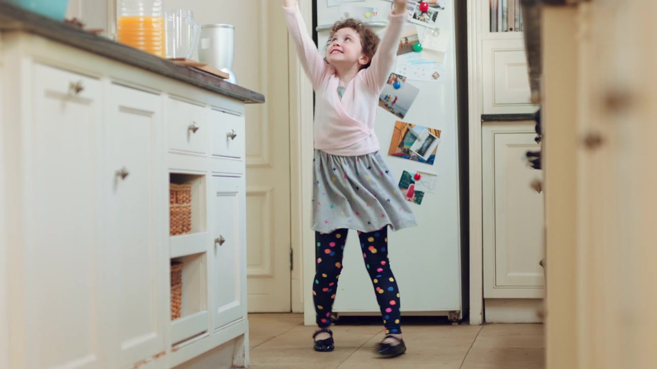 Little Girl Dancing and Playing with a Wand in the Kitchen