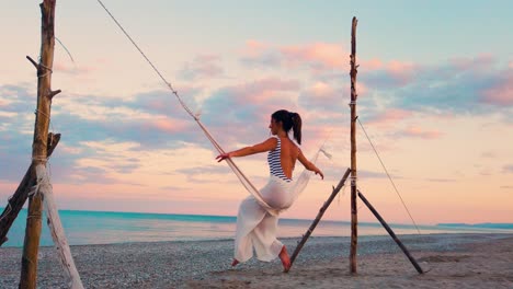 woman swinging on beach at sunset