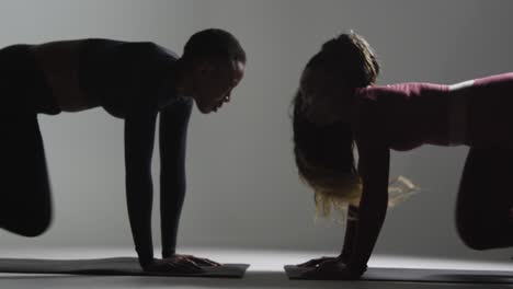 fotografía de estudio de dos mujeres con ropa de gimnasia frente a frente haciendo ejercicio 4