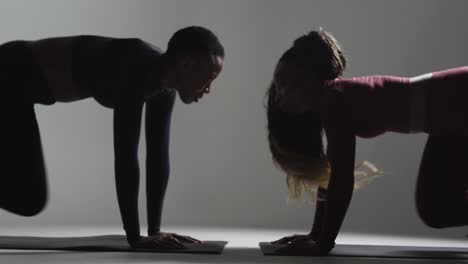 studio shot of two women wearing gym fitness clothing facing each other exercising 4