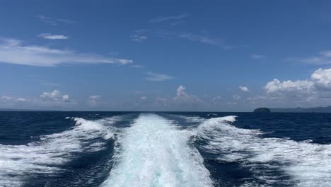 olas blancas como un rastro de una lancha rápida en el océano azul con cielos despejados