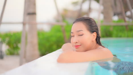 profile of beautiful exotic woman on swimming pool edge enjoying on lazy summer day, looking at camera, full frame slow motion