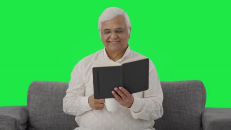 viejo indio feliz leyendo un libro y bebiendo té pantalla verde