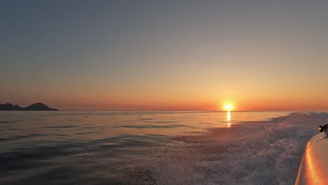 beautiful golden sunset on the horizon over sea as seen from moving navigating dinghy boat
